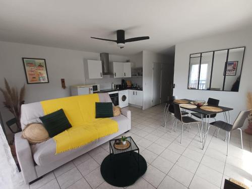 Una sala de estar con un sofá amarillo y una mesa. en L'Escapade Basque, en Hasparren