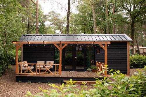 a wooden cabin with a table and a roof at Kapschuur in Zuidwolde