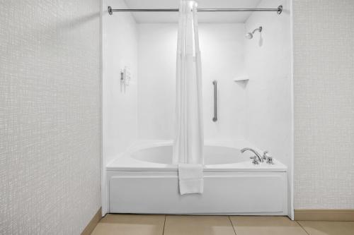 a white bathroom with a tub and a shower at Hampton Inn Bloomington West in Bloomington