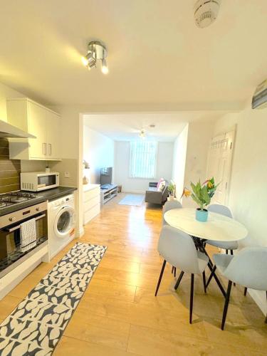 a kitchen and living room with a table and chairs at Modern 1 BR Apartment close to Emirates Stadium & City Links in London