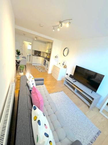 a living room with a couch and a flat screen tv at Modern 1 BR Apartment close to Emirates Stadium & City Links in London