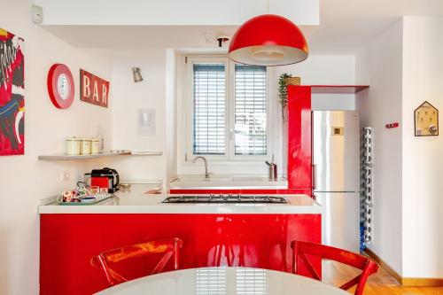 a red and white kitchen with a table and a refrigerator at Independent house private garden in Milan
