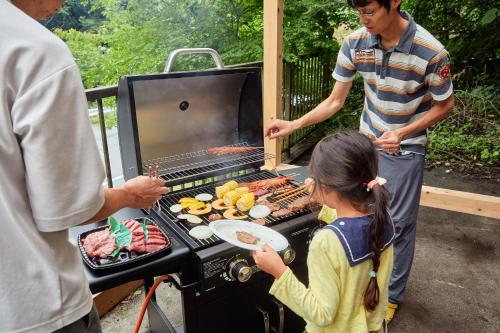 a man and a little girl cooking food on a grill at Hinosawa Riverside Lodge 水遊び宿日野沢 in Minano