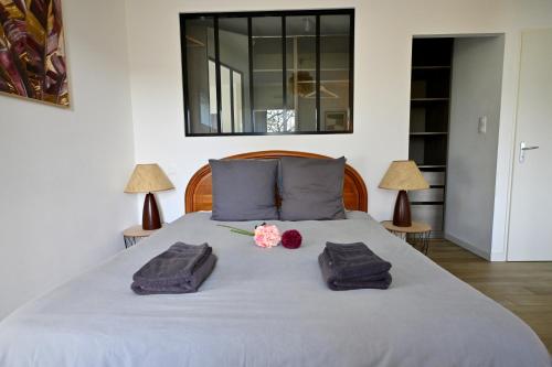 a bed with two towels and flowers on it at Maison moderne avec spa et jardin sans vis-à-vis, idéal professionnels et familles - L'ÉCRIN BRETON in Vannes