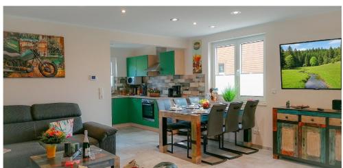 a living room with a table and a kitchen with green cabinets at Premium-Plus-Ferienhaus Skadi I in Hasselfelde