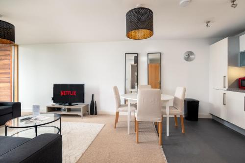 a living room with a table and white chairs at City Stay Apartments - Vizion in Milton Keynes