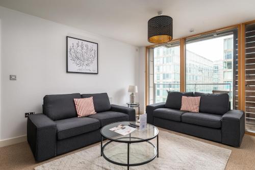 a living room with two black couches and a table at City Stay Apartments - Vizion in Milton Keynes