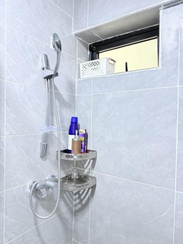 a shower in a white tiled bathroom with a shelf at The Kilimani Executive Studio Haven with Gym&Restaurant in Nairobi