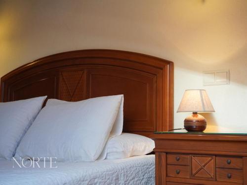 a bed with a wooden headboard and a table with a lamp at Casa Mayra in Camargo