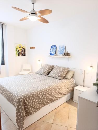a white bedroom with a bed and a ceiling fan at cozy flat in Puerto del Rosario