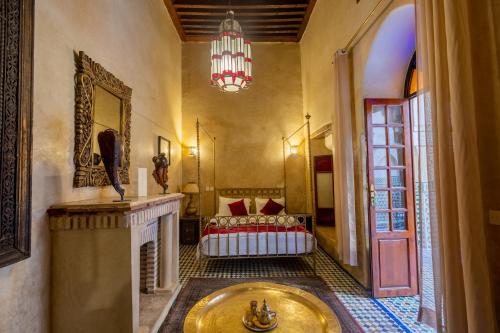 a room with a fireplace and a bed and a chandelier at Riad Sarasvati & SPA in Marrakesh