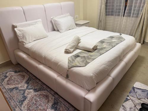 a white bed in a room with a couch at LionsGate Homes in Nakuru