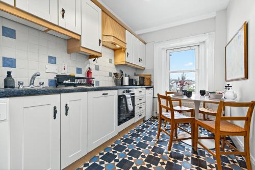 a kitchen with white cabinets and a table and chairs at Wolfe Tone Apartment 2 in Sligo