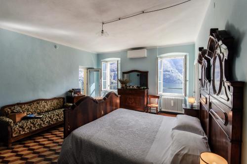 a bedroom with a bed and a couch and windows at Albergo Diffuso Ca' Spiga in Laglio