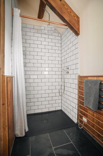 a bathroom with a shower with white tiled walls at The Stable at Widemouth Bay - 2 bedroom cottage both rooms twin or king in Poundstock