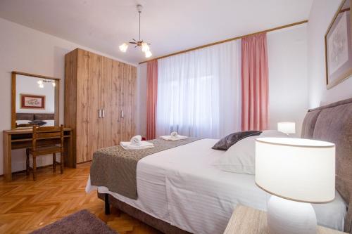 a bedroom with a bed and a desk in it at Apartments Dionis in Rab