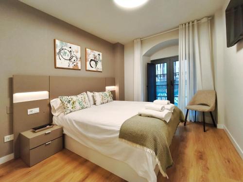 a bedroom with a large bed and a chair at Apt 1 hab Catedral III, Parking, Centro Valladolid in Valladolid