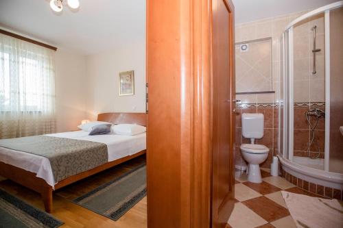 a bedroom with a bed and a bathroom with a toilet at Apartments Dionis in Rab