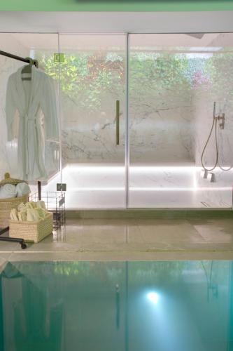 a bathroom with a shower and a sink and a robe at COCO-MAT Athens Jumelle in Athens