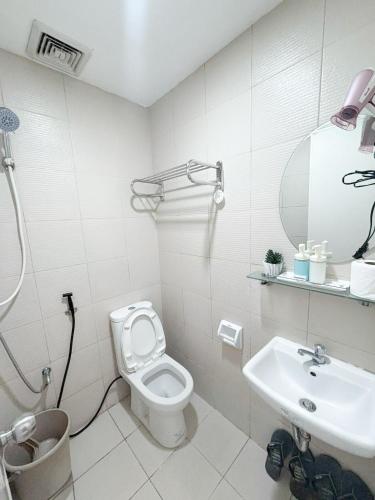 a white bathroom with a toilet and a sink at Woodland Tagaytay in Tagaytay