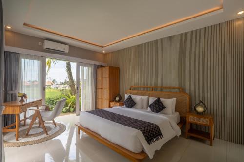 a bedroom with a bed and a desk and a window at Aksmi Suites & Villas in Bedahulu