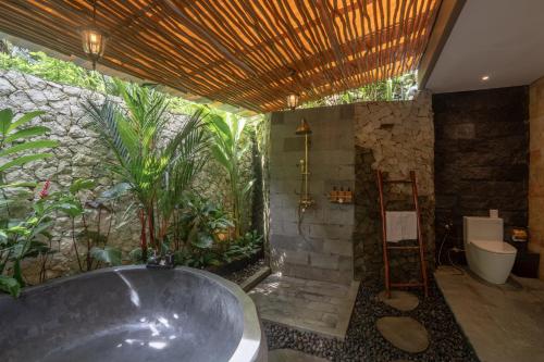 a bathroom with a bath tub and a garden at Aksmi Suites & Villas in Bedahulu