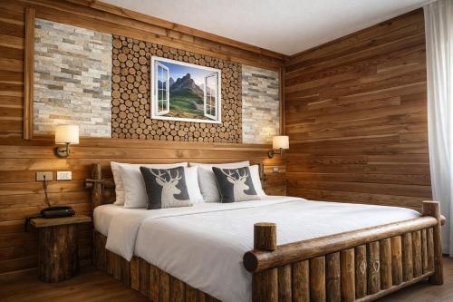 a bedroom with a large bed with wooden walls at Hotel Rododendro Val di Fassa in Campitello di Fassa