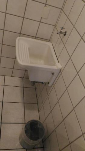 a white sink in a tiled bathroom with a drain at Apart Hotel Quartier Latin in Vitória