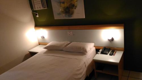 a hotel room with a bed and two night stands at Apart Hotel Quartier Latin in Vitória