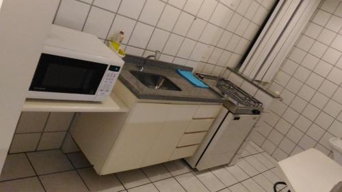 a small kitchen with a microwave and a sink at Apart Hotel Quartier Latin in Vitória