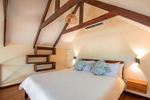 a bedroom with a large white bed with blue pillows at Complexo Palmeiras Bilene in Vila Praia Do Bilene