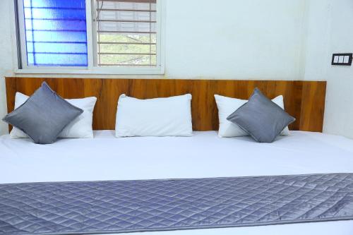 a bed with white pillows and a wooden headboard at Hotel Maharana Inn in Sehore