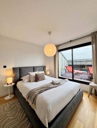 a bedroom with a large bed with a large window at La Maison Contemporaine, Luxe et Elégance aux portes de Rennes in Cesson-Sévigné