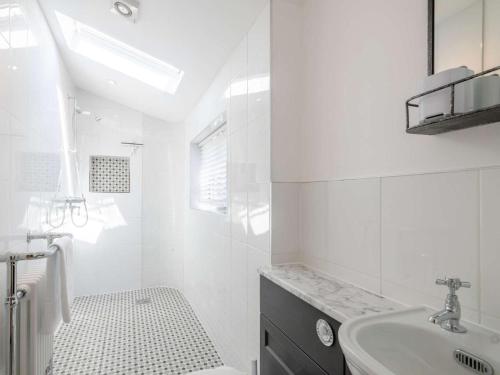 a white bathroom with a sink and a bath tub at 1 Bed in Holt oc-78233 in Cley next the Sea