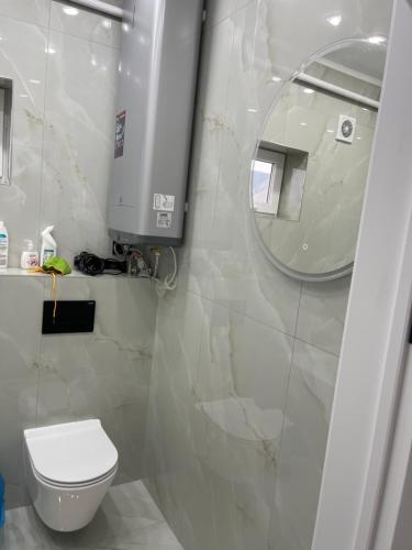 a bathroom with a white toilet and a mirror at Guest house Sayak in Bokonbayevo