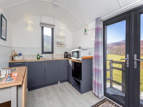 a kitchen with blue cabinets and a window with a view at Shepherds Hut - Uk49096 in Inchnadamph