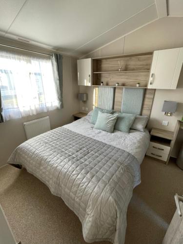 a bedroom with a large bed with blue pillows at Fairview Caravan Hire in Lossiemouth