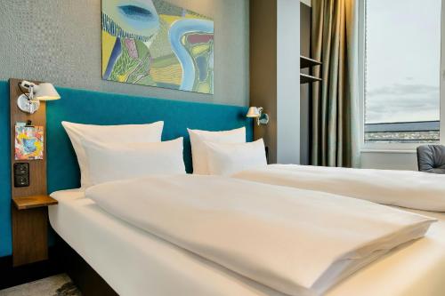 two beds in a hotel room with white pillows at Motel One Wiesbaden in Wiesbaden