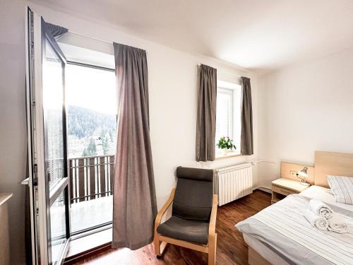 a bedroom with a bed and a chair and a window at Réva in Janske Lazne