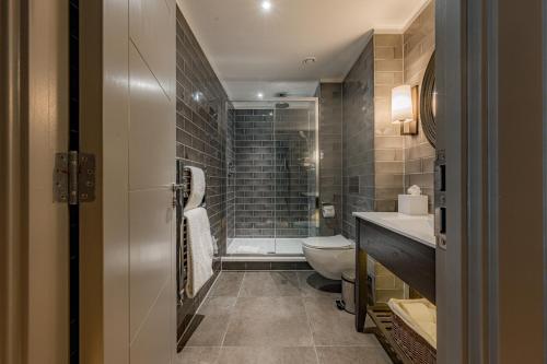 a bathroom with a shower and a toilet and a sink at Dakota Glasgow in Glasgow