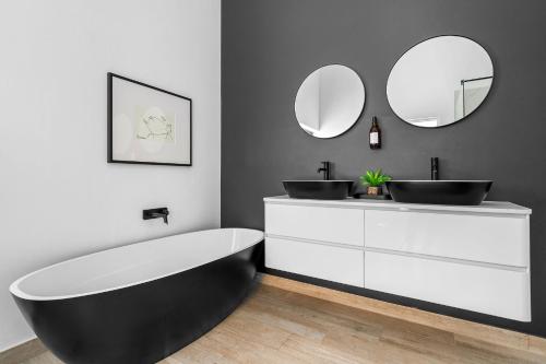 a bathroom with a black and white tub and two mirrors at Villa View in Stompneusbaai