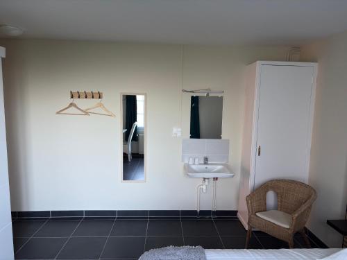 a bedroom with a sink and a chair and a mirror at Hôtel L'escale des Hayons in Esclavelles