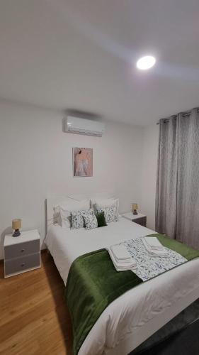 a bedroom with a large bed with a green blanket at Pôr do Sol II in Porto Moniz