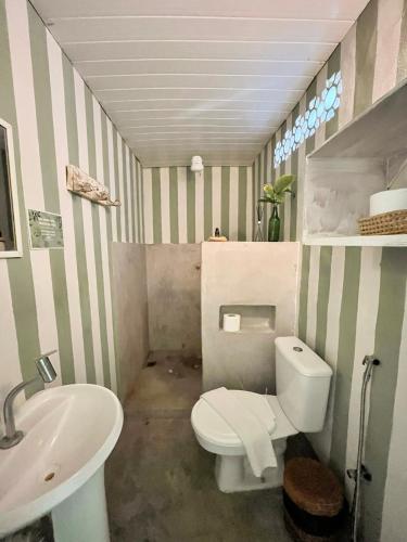 a bathroom with a white toilet and a sink at Pousada Jardim da Praça in Caraíva