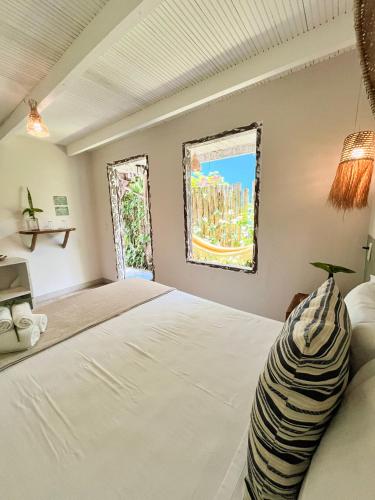 a bedroom with a bed and a window at Pousada Jardim da Praça in Caraíva