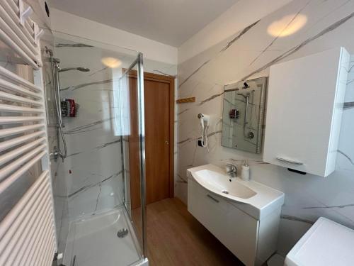 a white bathroom with a sink and a shower at Like Heaven Argegno Pool & Lake View in Argegno