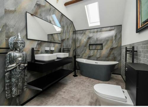 a bathroom with a statue next to a sink and a tub at Sandstone Grange in Albrighton