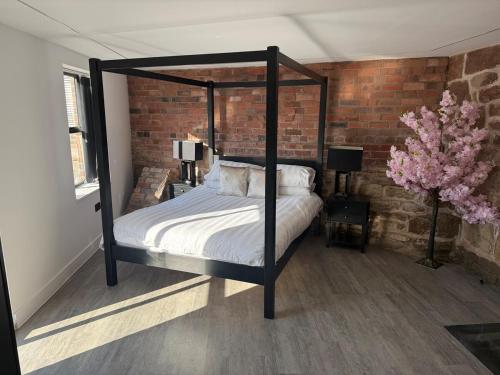a bedroom with a canopy bed with a brick wall at Sandstone Grange in Albrighton