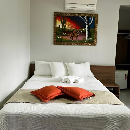 a bed with two pillows and a picture on the wall at Pousada Lagoa Seca in Juazeiro do Norte