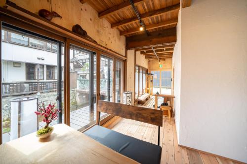 a room with a table and chairs and windows at 長浜ゲストハウスミカタ Guest House Mikata in Nagahama